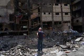 مردی در 17 آوریل در محل حمله اسراییل به یک ساختمان مسکونی در بیروت خسارات وارده را مشاهده می کند.